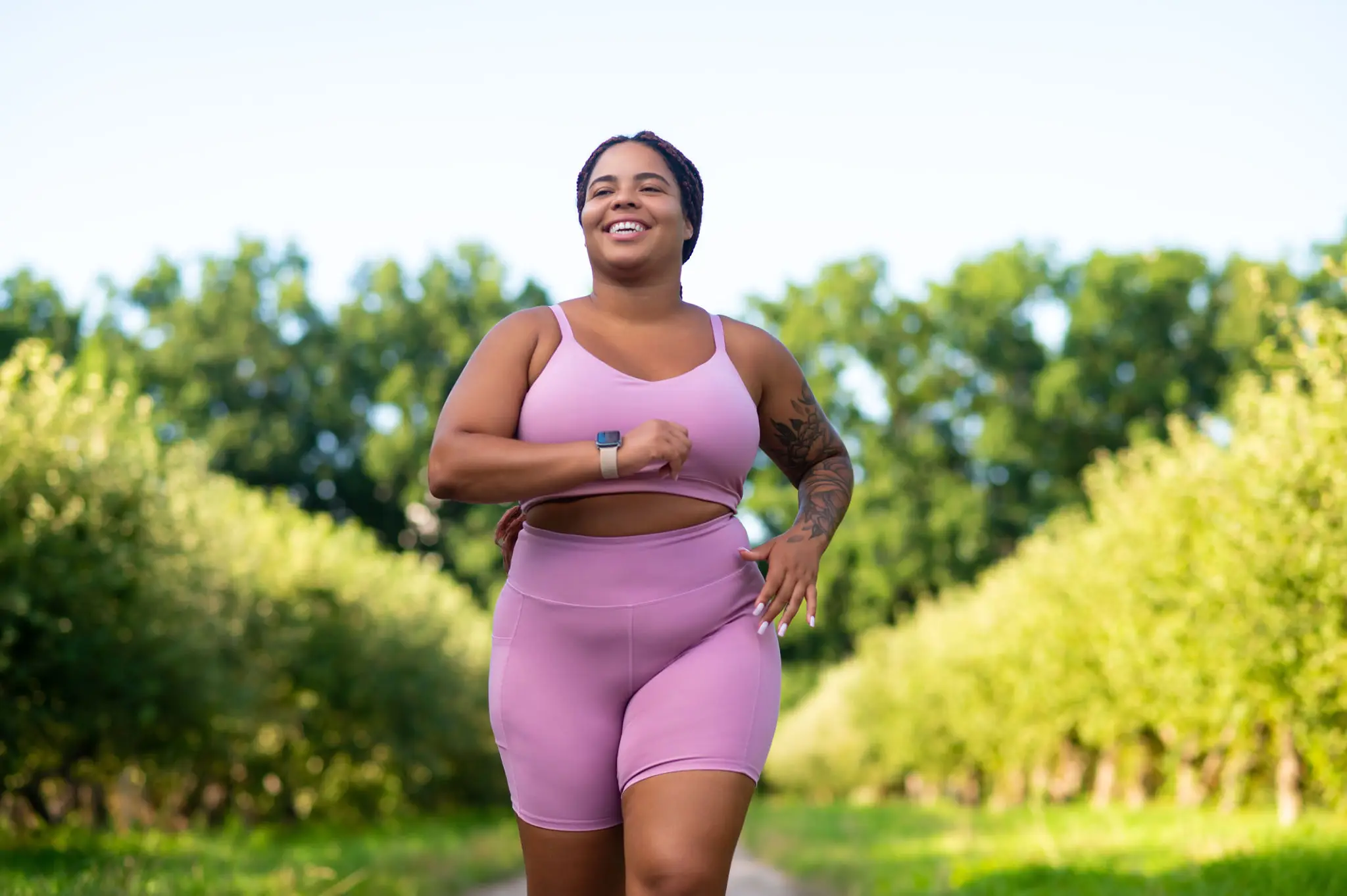 Confident woman jogging outdoors in pink activewear.